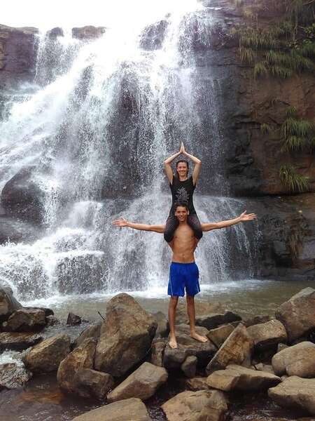 travellers yoga posing in front of waterfall