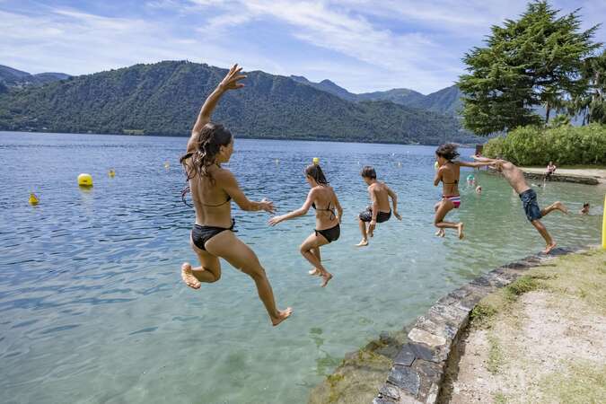 people jumping from a pier into the lake in the mountains