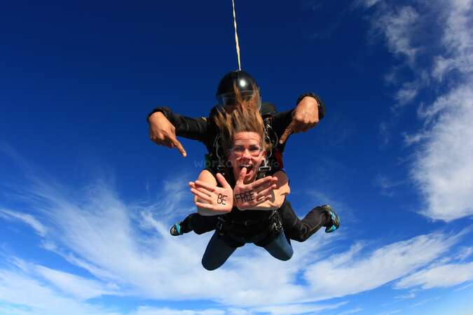 lady sky diving with be free written on her hands