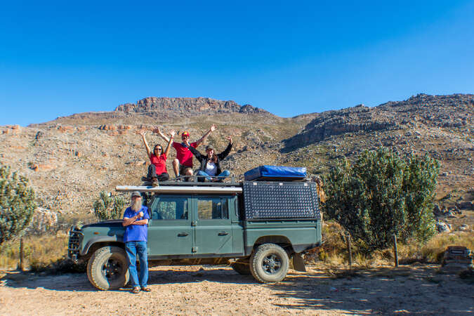 group of friends posing on top of a jeep in the mountains