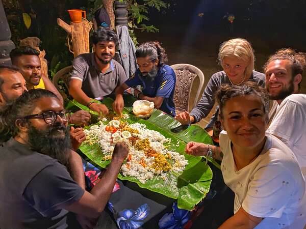 group of volunteers eating meal from leaf