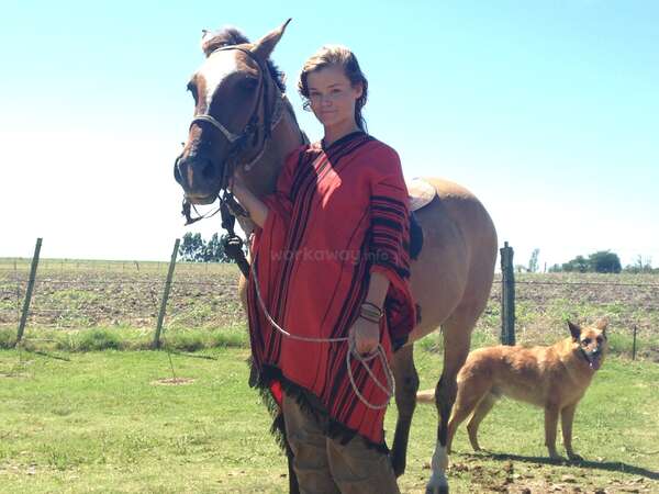 solo female wearing poncho and riding horse in uruguay