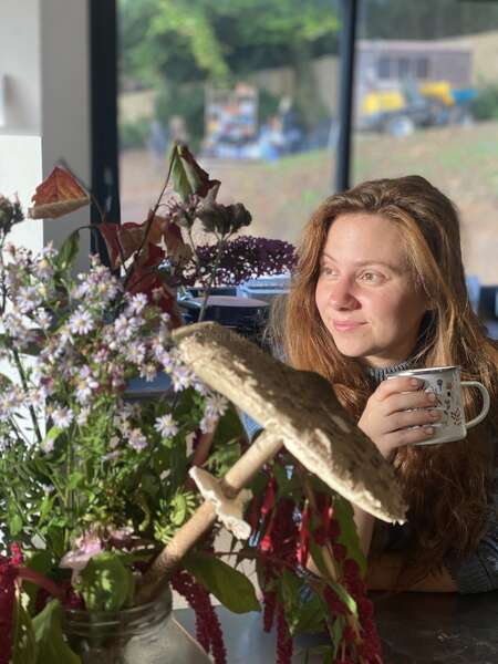 solo female drinking tea from mug next to plants