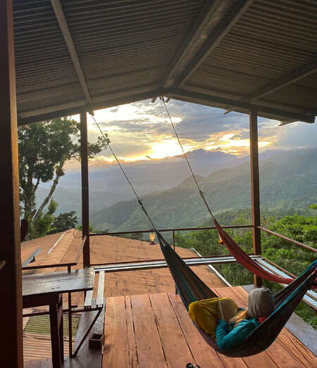 solo traveller reading in a hammock with mountain view