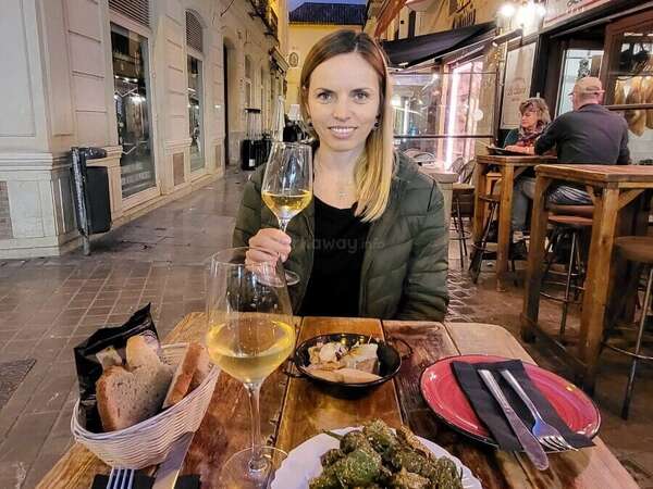 Angelina, the article's author, sits in the evening in a tapas bar in Malaga with a glass of white wine