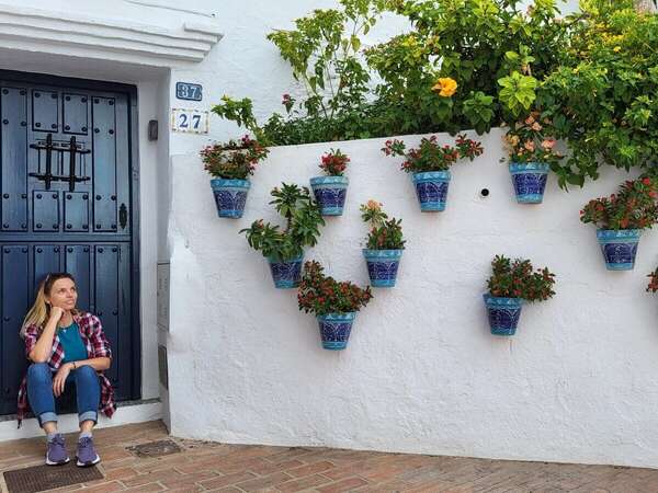 Angelina, the article's author, sits on the doorstep of a white house in a village of Mijas in Andalusia.