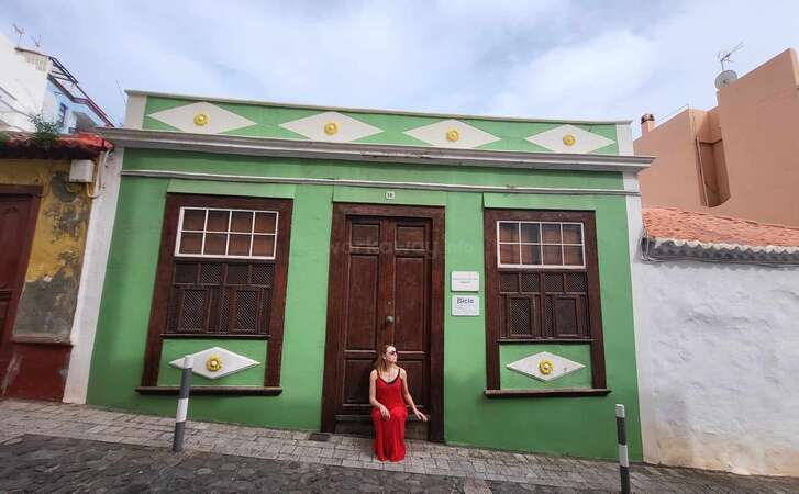 Angelina, the blog post author, sits on the doorstep of a colorful house in Santa Cruza de la Palma, La Palma, Canary Islands