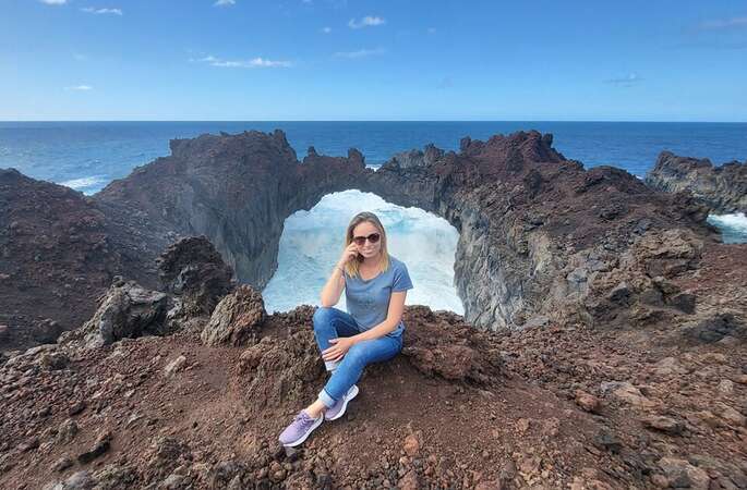 Angelina, the blog post author, sits on the rocks with the ocean in the backgrouns in El Hierro, Canary Islands, Spain