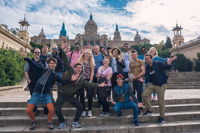 A group of happy Workawayers pose for a photo in Barcelona with the Castillo de Montjuïc in the background.