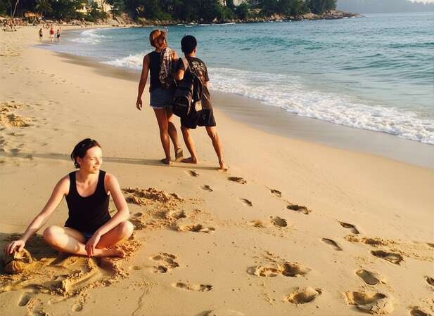 Angelina, la autora de la entrada del blog, está sentada en la arena al atardecer, en la playa de Phuket, Tailandia.
